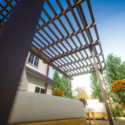 Looking up at a brown pergola from a seating area below
