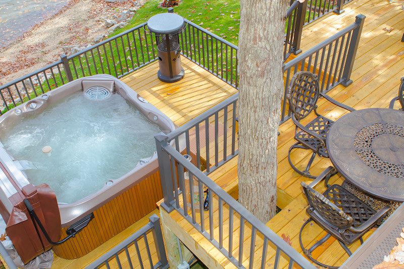 Hot tub on a wooden deck with metal railings, viewed from above