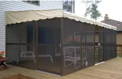Screen room with a beige scalloped canopy roof on a wooden deck beside a house