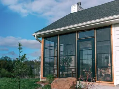 Sunroom with dark framed glass walls and a shingled roof