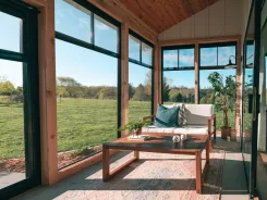 Sunroom interior with timber framing, sofa and coffee table looking onto fields