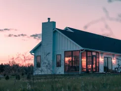 House with a lit sunroom extension at dusk