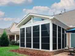 White framed sunroom with a peaked roof attached to a house