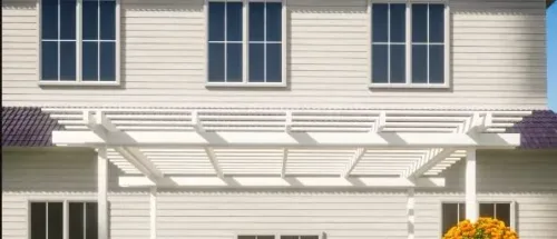 White pergola attached to a sided house above a patio