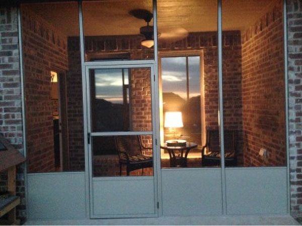 Looking through a screened porch to a lit interior at dusk
