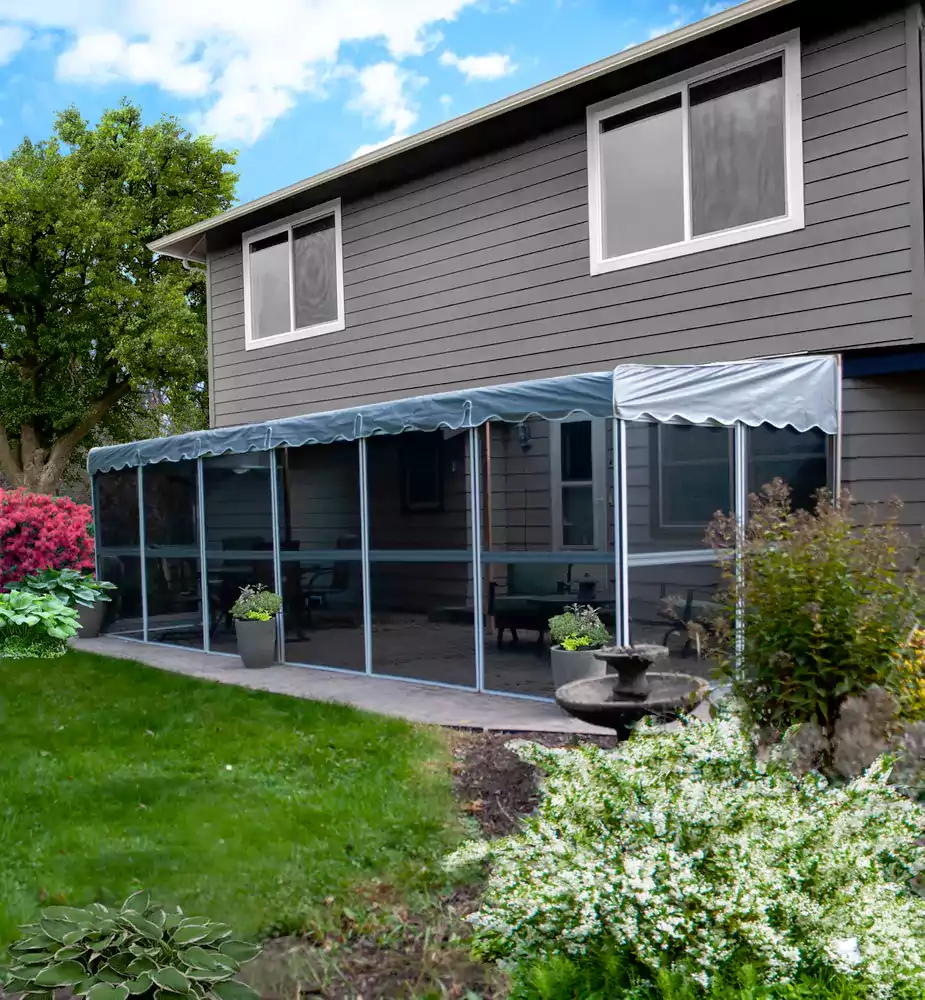 Screen room with a blue scalloped canopy roof along the back of a grey house