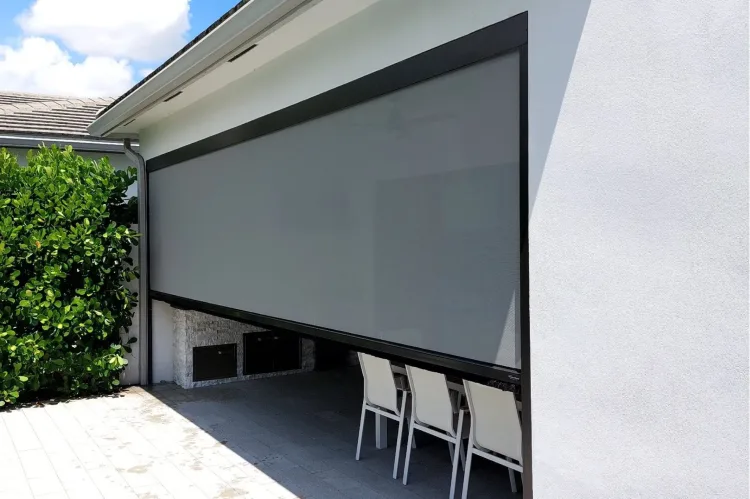 Motorised solar screen lowered across a covered patio opening