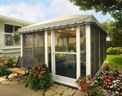 Screen room with a scalloped awning roof and flower beds beside a house