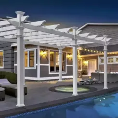 White pergola with string lights over a poolside patio at dusk