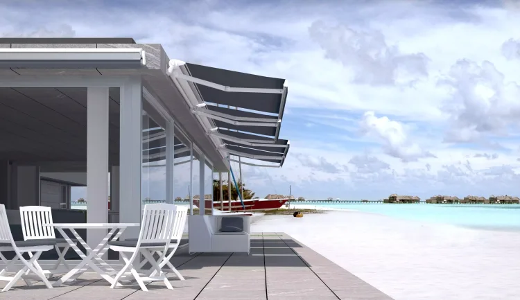 Retractable awnings shading a terrace overlooking a turquoise sea