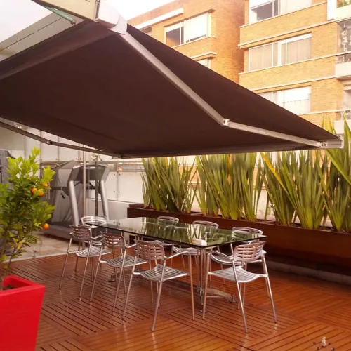 Dark retractable awning shading a rooftop terrace with tables and chairs