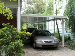 Carport with a clear polycarbonate roof sheltering a car beside a house