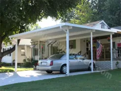 White carport beside a house with a car parked beneath and a flag on the porch