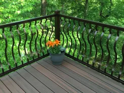Deck corner with curved metal balusters and a potted plant