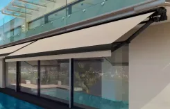 Retractable awning extended over a poolside terrace of a modern house