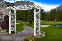 White Fairfield Grande arbour with climbing vines beside a golf course path