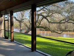 Screened patio opening looking out over a river and oak trees