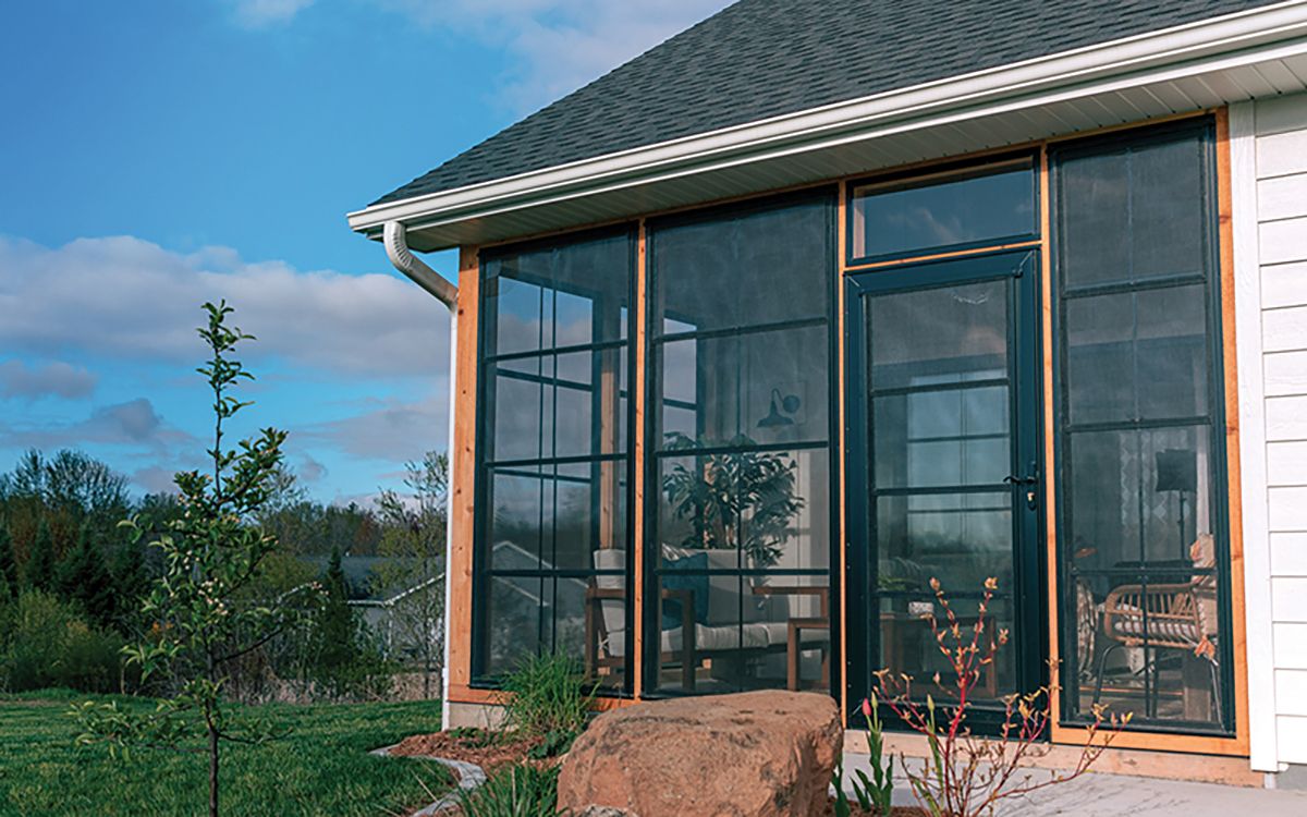 Sunroom with dark framed floor-to-ceiling glass attached to a house