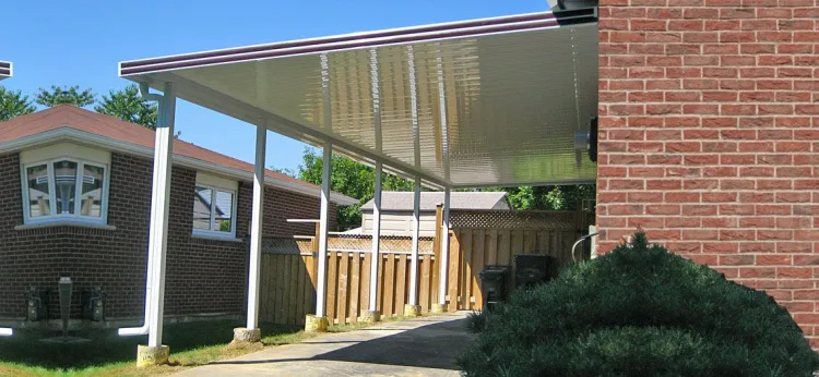 White carport between a brick wall and a house