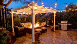 Pergola lit with string lights over an outdoor lounge and fire pit at dusk