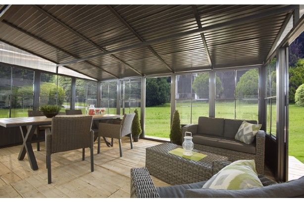 Inside a screen room with a corrugated ceiling, dining table and lounge seating