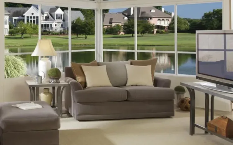Sunroom interior with lipframe windows, a sofa and a lake view