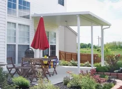 White patio cover over a patio with a red parasol and dining set