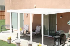 White patio cover over a stucco house patio with seating and a barbecue