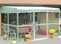 Family seated at a table inside a PatioMate screen enclosure with a green canopy