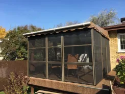 Screen room with a scalloped canopy roof beside a brick house