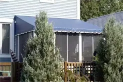 Screen room with a navy canopy roof on a deck behind conifers
