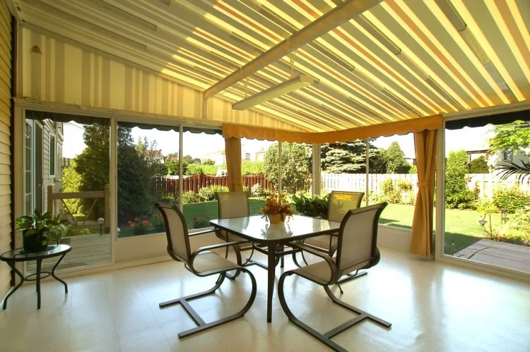 Underside of a louvred patio cover over a paved dining area with curtains