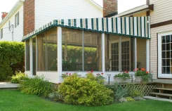 Polaria screen room with a green striped awning roof and flower beds along the front