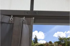 Close-up of a drop curtain and rail on a clear polycarbonate patio cover