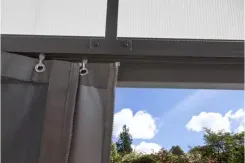 Close-up of a drop curtain hanging from a patio cover rail on rings