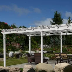 Long white pergola over a patio dining set beside a rock garden