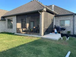 Screened porch on a brick house with a dog on the lawn outside