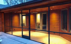 Lit screened verandah with timber cladding beside a pool at night