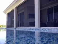 Retractable screens along a poolside terrace at dusk