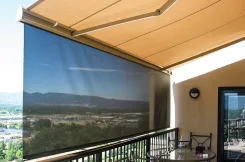 Retractable awning with a solar drop curtain shading a balcony above a valley