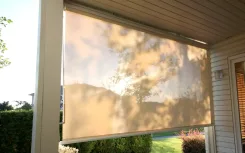 Exterior solar shade lowered across a porch opening, daylight filtering through the mesh