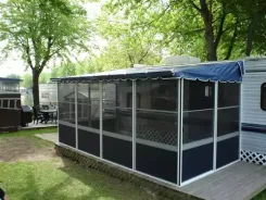 Screen room with a navy awning roof attached to a caravan on a lawn