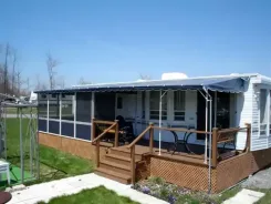 Screen room with a navy awning roof and wooden steps along a mobile home