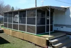 Screen room with dark screens and lattice skirting attached to a caravan