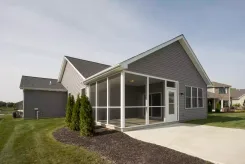 Screened porch built into the corner of a grey sided house