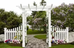 White Fairfield arbour with picket fence wings over a paved path
